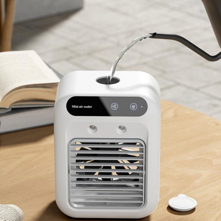 Air Conditioner Air Cooler Fan on a wooden table with a book, featuring a water filling slot and fan grill.